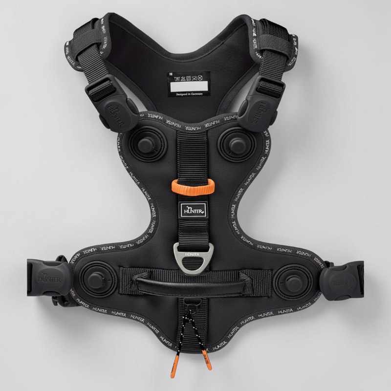 Black ErgoMove Pro ergonomic dog harness, flat-cut design, with reflective Hunter lettering and orange accents. Padded Y-shaped chest strap, back pad with handle, adjustable straps and D-ring.