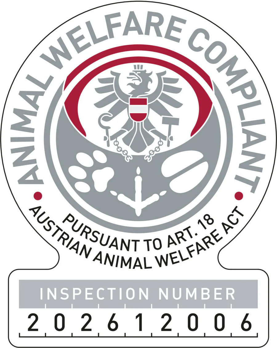 Marchio rotondo con aquila federale austriaca e simboli benessere animale (zampa, zampa d'uccello, zoccolo). Testo: ANIMAL WELFARE COMPLIANT PURSUANT TO ART. 18 AUSTRIAN ANIMAL WELFARE ACT. In basso n. 202612006. Conformità legge.