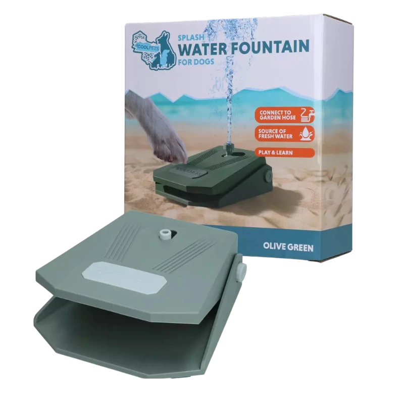 Distributore d'acqua per cani color verde oliva, leggermente aperto nella parte anteriore. Sullo sfondo la confezione: un cane aziona il distributore su un terreno sabbioso con la zampa, da cui sgorga un getto d'acqua fresca. Per giocare e bere.