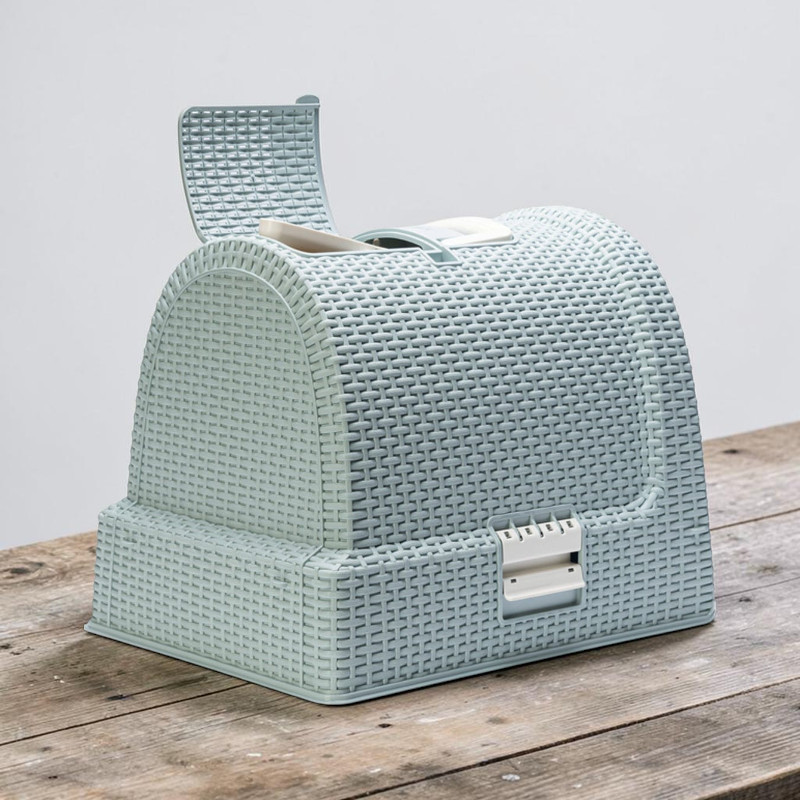 Enclosed cat litter tray in matt light blue with a woven rattan-effect finish on a rustic wooden base. Features a domed lid, a flap for the litter scoop and a carrying handle. Two white fasteners at the front for the litter drawer.