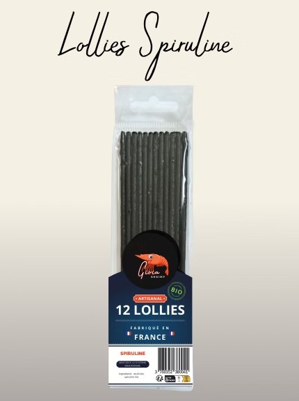 Confezione trasparente contenente dodici lecca-lecca di colore grigio scuro a forma di bastoncino. Etichetta frontale: logo "Gloria Shrimp" arancione su sfondo nero, con sotto la scritta "12 Lollies" e "Fabriqué en France". In alto: "Lollies Spiruline".