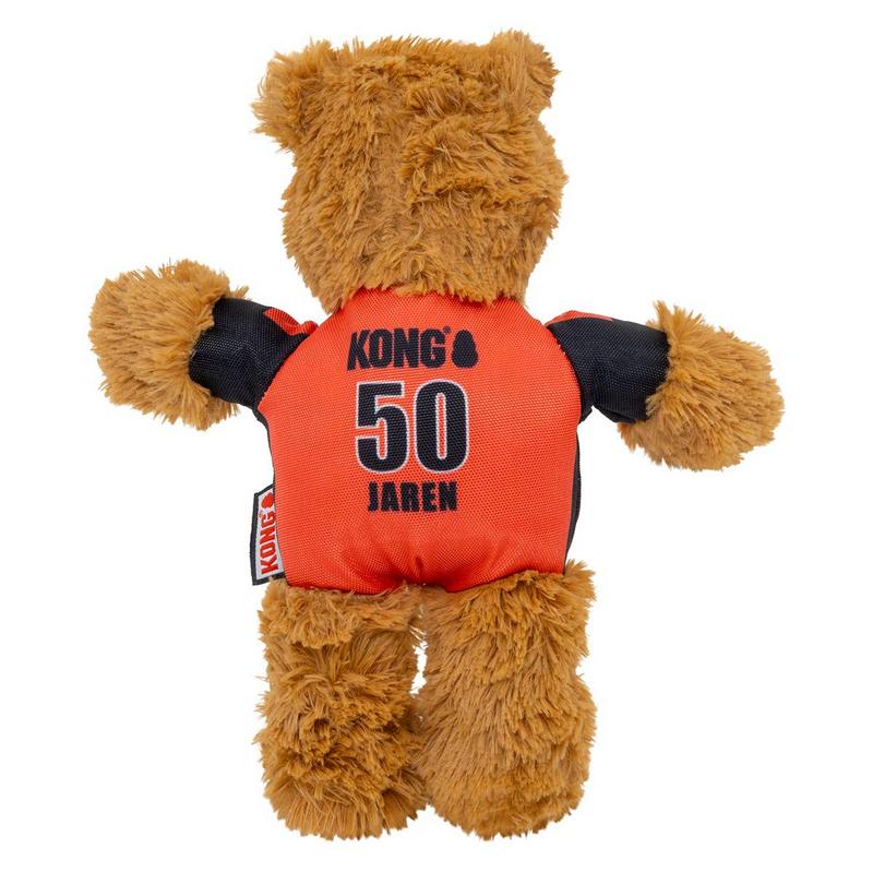 Morbido orsacchiotto marrone di spalle all'osservatore. Indossa una maglietta arancione e nera con una grande stampa "Kong", "50" e "JAREN" sul retro. Sulla sinistra è appesa un'etichetta Kong (anniversario/edizione).