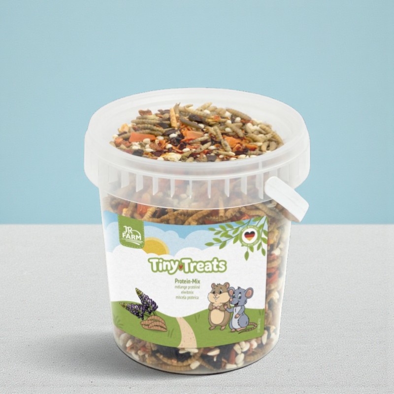 Ein durchsichtiger Behälter voll mit JR Farm Tiny Treats Protein-Mix, einem Nager-Snack. Das Etikett zeigt eine Lupine und Nagetiere.