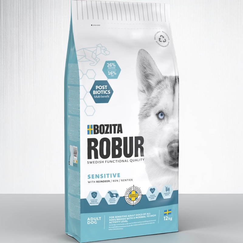 Emballage vertical bleu clair et blanc de la gamme « Robur Adult Sensitive Reindeer » pour chiens. Une tête de husky blanche aux yeux bleus orne le devant. Informations clés : sans céréales, postbiotiques, 26 % de protéines, 12 kg, fabriqué en Suède.