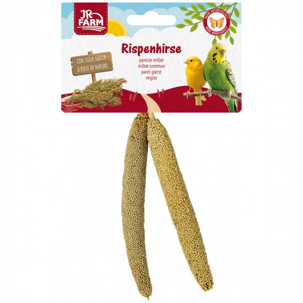 Zwei goldbraune Rispenhirse-Stängel mit kleinen Körnern hängen an einer Packung. Sie zeigt das JR FARM Logo, 'Rispenhirse', einen gelben Kanarienvogel und einen grünen Wellensittich. Links: Holzschild 'EIN STÜCK NATUR'.