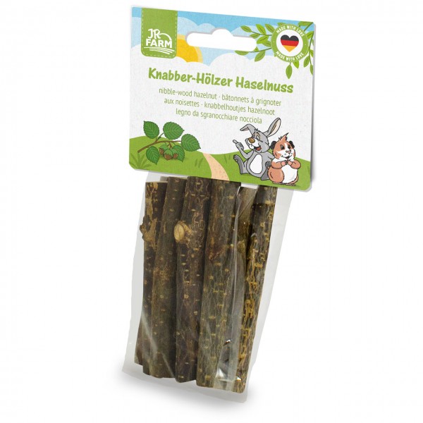 Transparente Packung JR FARM Knapper-Hölzer Haselnuss mit mehreren dunkelbraunen, naturbelassenen Holzstücken zum Nagen für Kleintiere. Weißer Karton-Header mit Haselnusszweig, Hase und Meerschweinchen.