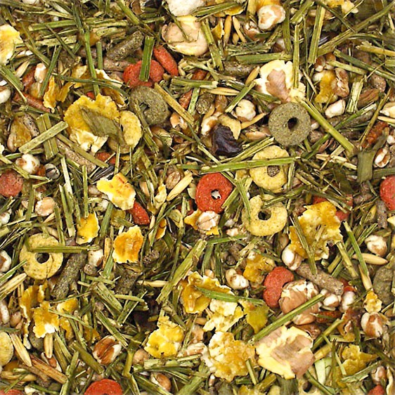 A colourful mix of dry pet food: green strands of hay, orange carrot pieces, yellow and red cereal rings, oat flakes and pellets. Densely packed, with a varied texture. A balanced muesli for small animals.