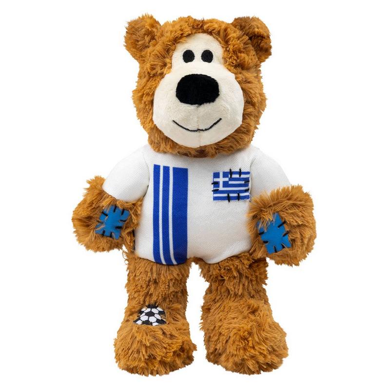 Ein brauner, flauschiger Teddybär steht aufrecht und lächelt. Er trägt ein weißes T-Shirt mit zwei blauen Streifen und einer kleinen griechischen Flagge auf der Brust. An den Händen hat er blaue Stern-Patches und am linken Fuß einen Fußball-Patch.