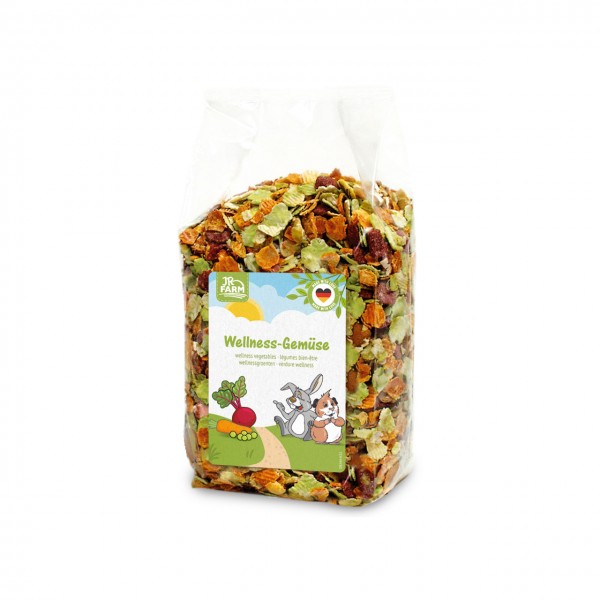 Durchsichtige Plastiktüte mit kleinen, getrockneten Gemüsestücken in Grün-, Orange- und Brauntönen. Etikett mit JR FARM-Logo, „Wellness-Gemüse“, Hase, Meerschweinchen, Karotten und Rübe. Made in Germany-Siegel.