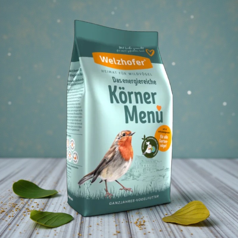 Verpackung Welzhofer Körner-Menü mit Rotkehlchen-Illustration, Ganzjahres-Vogelfutter auf hellem Holztisch.