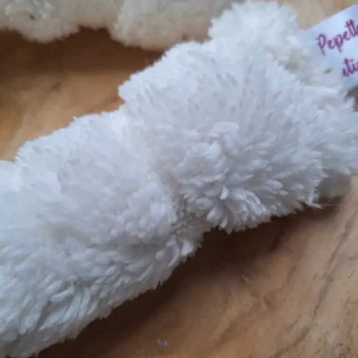 Nahaufnahme eines flauschigen, weißen Stirnbandes mit einem kleinen, violetten Etikett.