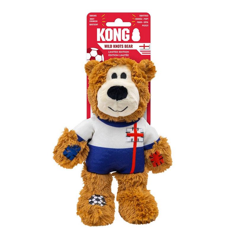 Orsacchiotto di peluche marrone con maglietta a righe bianche e blu e una croce rossa sul petto. Piede sinistro con toppa a forma di pallone da calcio; fissato su una confezione rossa Kong per un giocattolo in edizione limitata, su sfondo bianco.