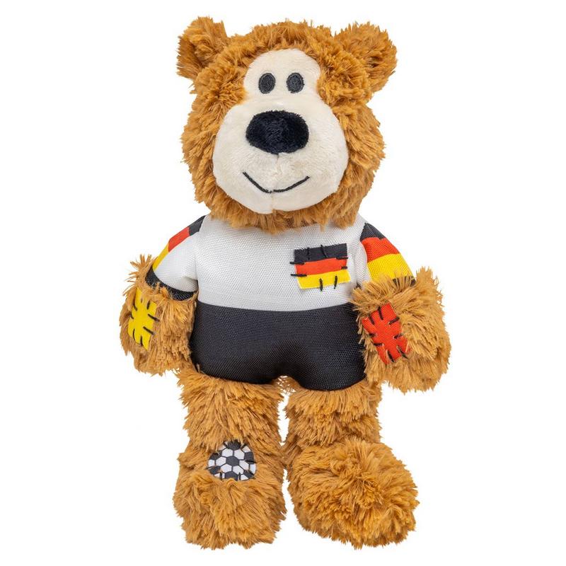 Morbido orsacchiotto marrone eretto, con maglia bianca a maniche nere e nastri nero-rosso-oro. Piccola bandiera tedesca sul petto. Toppe colorate su braccia e gambe, pallone sulla gamba sinistra. Espressione simpatica.