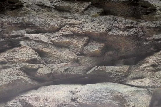 Eine Nahaufnahme einer grauen Felswand mit rauher, unebener Textur.