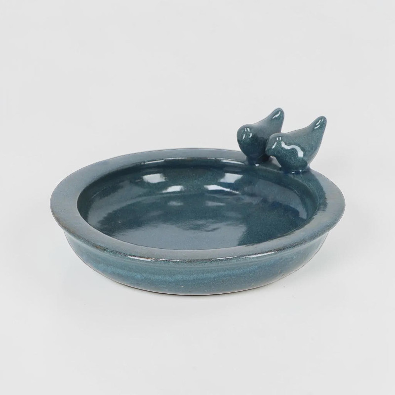 Abreuvoir rond pour oiseaux en céramique brillante couleur pétrole, idéal pour abreuver et baigner les oiseaux sauvages. Le bord surélevé du bol est décoré de deux petites figurines d'oiseaux stylisées.