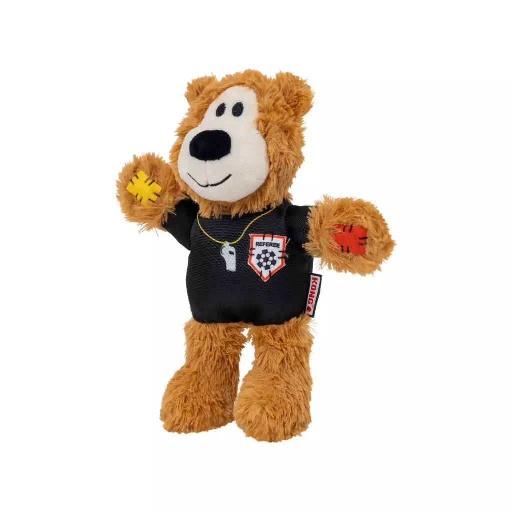 Orsacchiotto di peluche marrone vestito da arbitro di calcio. Indossa maglia nera con scritta "REFEREE" e stemma con pallone a scacchi. Fischietto bianco al collo. Cartellino giallo a sinistra, rosso a destra. Bocca bianca, espressione simpatica.