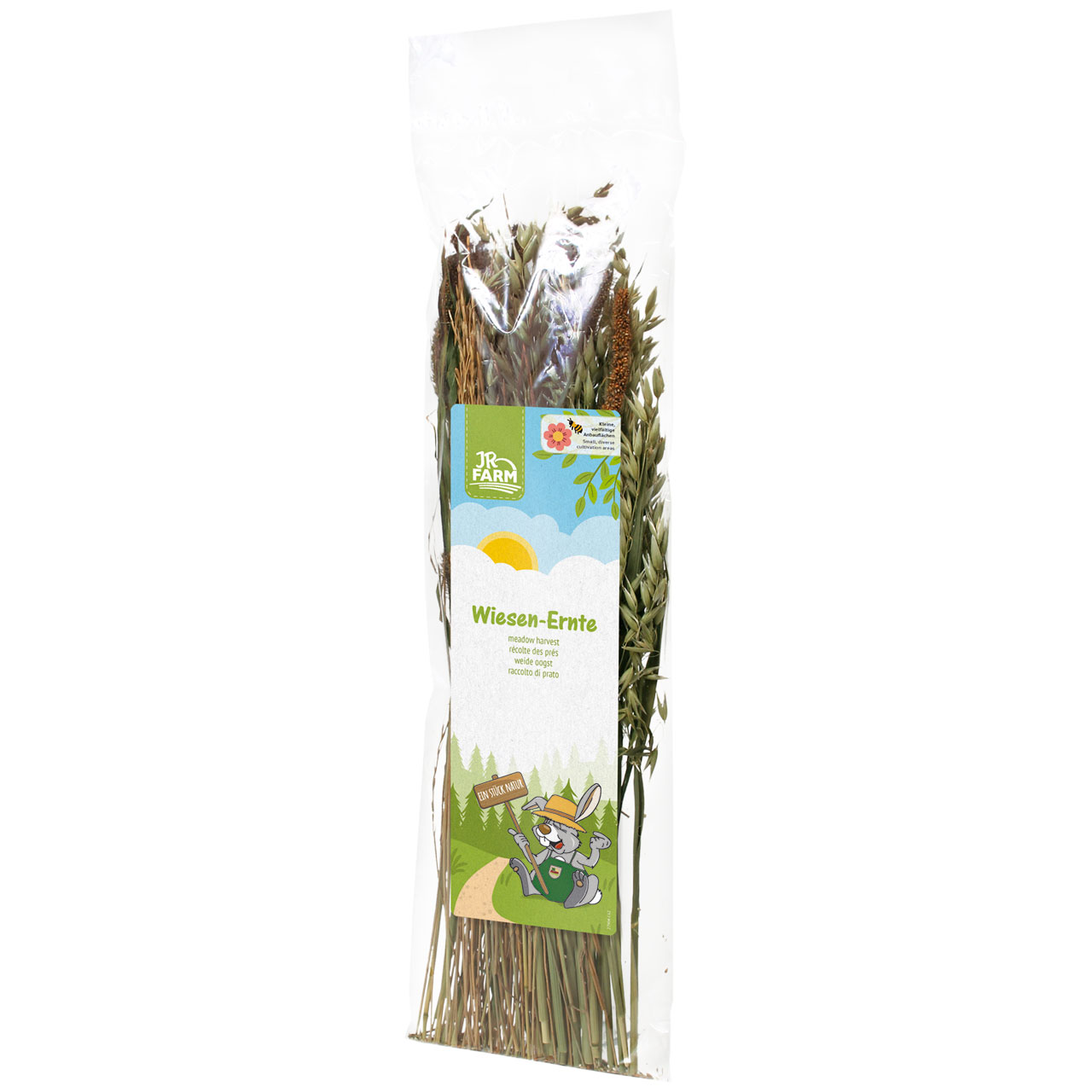 Transparent plastic bag containing dried green and brown grasses and herbs. Label: blue sky with clouds/sun, ‘JR Farm’ logo, text ‘Meadow Harvest’, cartoon rabbit with ‘A piece of nature’. Pet food.