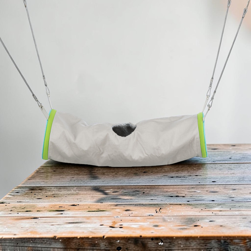 Ein weicher, grauer Kuscheltunnel aus Nylon für Frettchen, Ratten oder Chinchillas hängt über Holz. Grüne und türkisfarbene Ränder an den Öffnungen, oben mittig eine ovale Einstiegsöffnung. Vier Seile mit Karabinern.