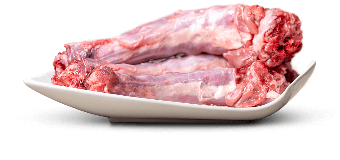 Pezzi di carne cruda di collo d'agnello o capra con osso sono disposti su un piatto bianco ricurvo. La carne varia dal rosa-rossastro al rosso scuro, con tendini e grasso bianco-argenteo.