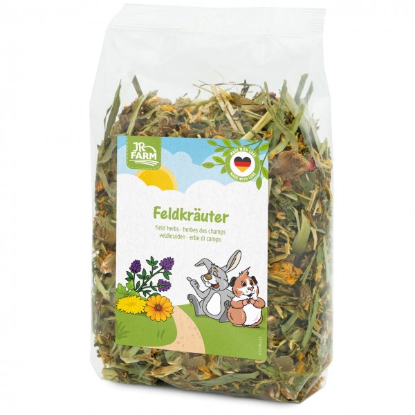 Transparente Verpackung mit JR Farm Feldkräutern: Mischung aus getrockneten Gräsern, Kräutern und Blüten wie Ringelblumen. Etikett mit Hase und Meerschweinchen auf Blumenwiese, Produktname „Feldkräuter“, „Made with Love“ und deutscher Flagge.
