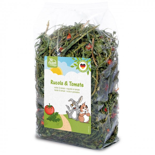 Transparent bag of dried green rocket and red tomato pieces for small animals. ‘JR Farm Rocket & Tomato’ label shows cartoon rabbits, guinea pigs, a tomato and rocket leaves, plus a ‘Made in Germany’ seal.
