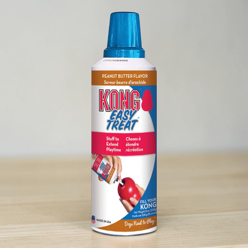 Aufrechte weiße/braune Spraydose KONG Easy Treat mit blauem Sprühkopf. Enthält Erdnussbutter-Snackpaste für Hunde zum Befüllen von KONG Spielzeugen. Vorderseite: Hand füllt rotes KONG Spielzeug. 226 g.