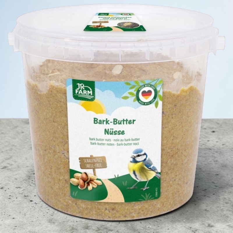 Large transparent bucket of nut and bark butter for wild birds. Label: JR Farm Bark Butter – nuts, blue tit and peanuts. Note: ‘SHELL-FREE’. Grainy butter with visible pieces of nut, high in energy.