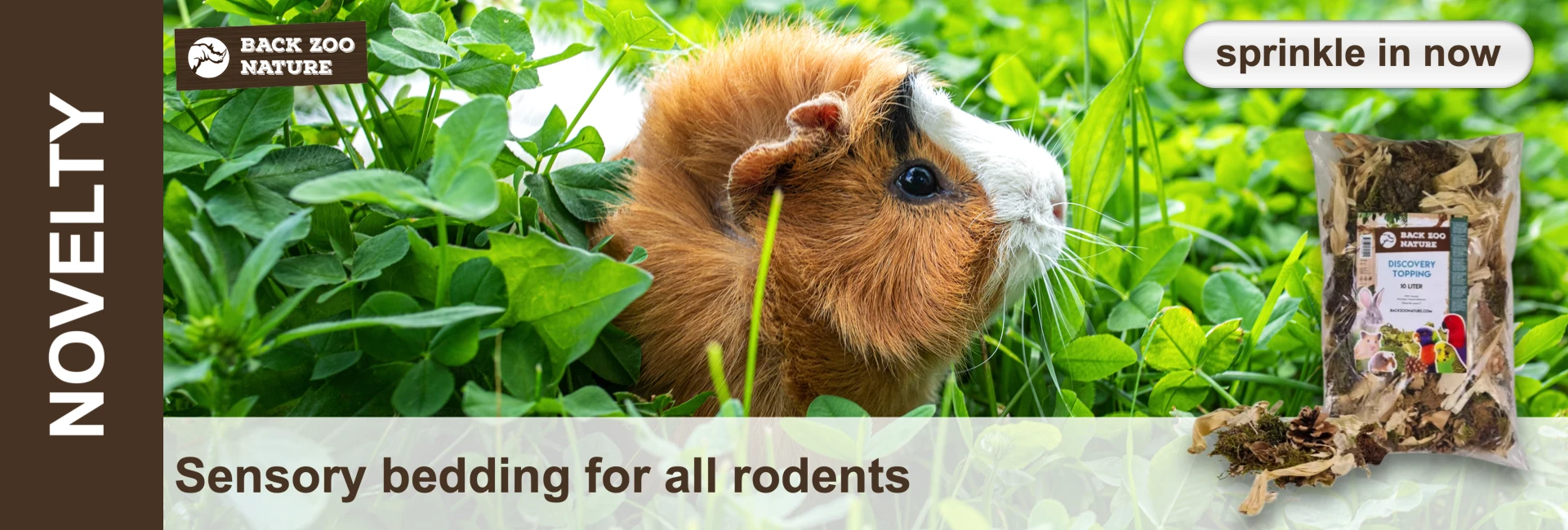 A brown and white guinea pig sits in green clover; on the right a packet of bedding with pictures of animals.