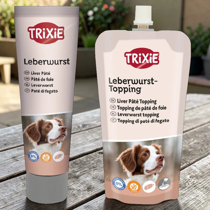 Un tubo e un sacchetto di salsiccia di fegato per cani Trixie, entrambi con l'immagine di un cane, si trovano su un tavolo di legno.