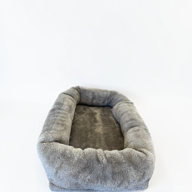 Ein rechteckiges, graues Haustierbett mit weichem, flauschigem Stoff und erhöhten, gepolsterten Rändern. Das Innere ist ein dunklerer Grauton und lädt zum Schlafen ein. Das gemütliche Bett steht auf einem schlichten weißen Hintergrund.