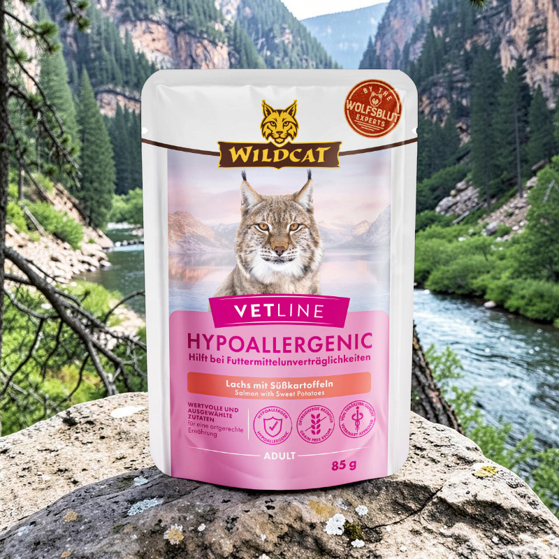 White and pink ‘ Wildcat ’ bag. Vetline Hypoallergenic Cat Food on a rock. On the packet: a lynx, ‘Salmon with Sweet Potatoes’ and ‘Helps with food intolerances’. Behind it, a mountain landscape with a river and green trees.