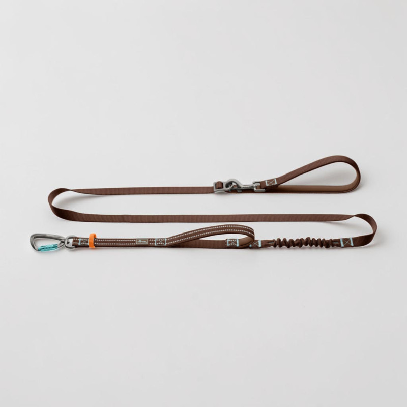 Braune Hunter Action-Leine ErgoMove Pro auf weißem Hintergrund flach ausgelegt. Mit Aluminium-Sicherheitskarabiner vorne, feinen reflektierenden Stichlinien, Polsterung, integriertem Ruckdämpfer und verstellbarer Handschlaufe.