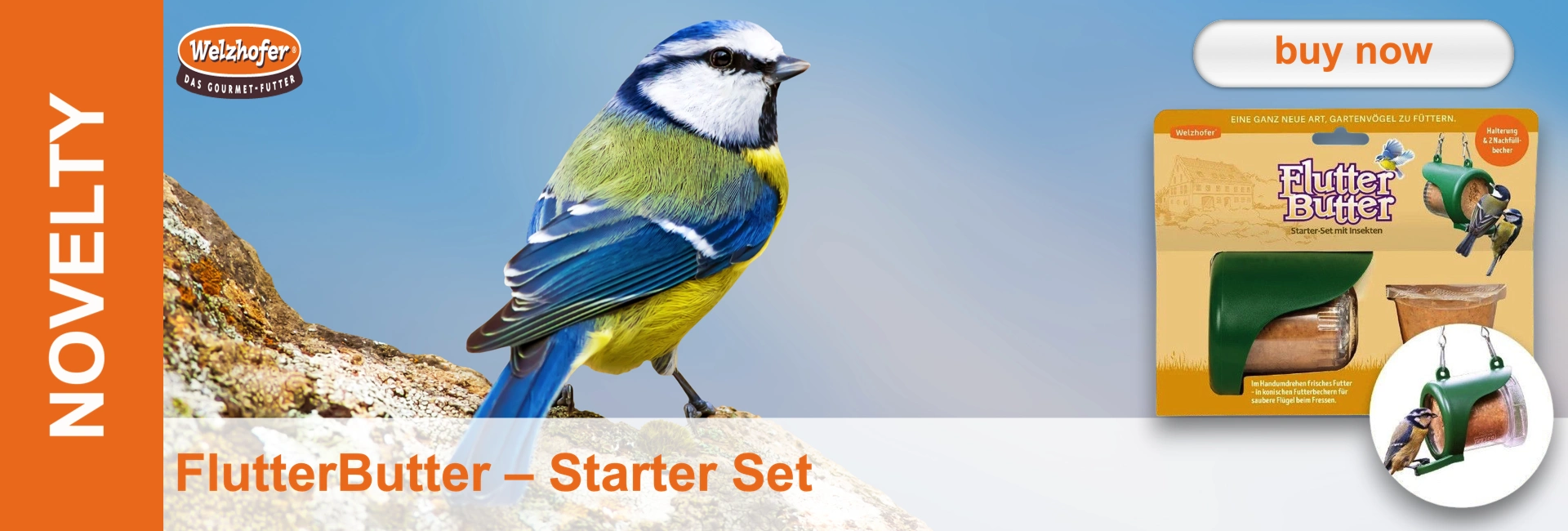 A colourful blue tit with blue wings, a yellow breast and a white head perches on a moss-covered rock against a blue sky. Next to it is the packaging for the Welzhofer FlutterButter Starter Set, containing insect food and a green feeder.