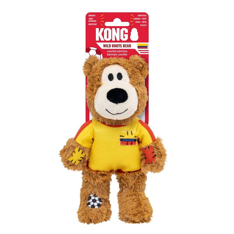 Orsacchiotto di peluche marrone, giocattolo per cani Kong Wild Knots Bear, con maglia da calcio gialla a maniche rosse e piccola toppa a bandiera. Zampe con toppe rosse e gialle; sul piede sinistro toppa a pallone.