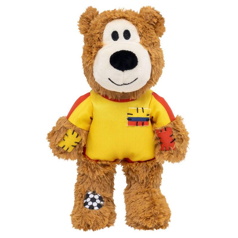 Orsacchiotto di peluche marrone con maglietta gialla con strisce rosse sulle maniche. Sul petto una toppa a strisce gialle, blu e rosse. Zampe con toppe rosse/gialle, sulla gamba sinistra una toppa a forma di pallone da calcio. Faccia sorridente.