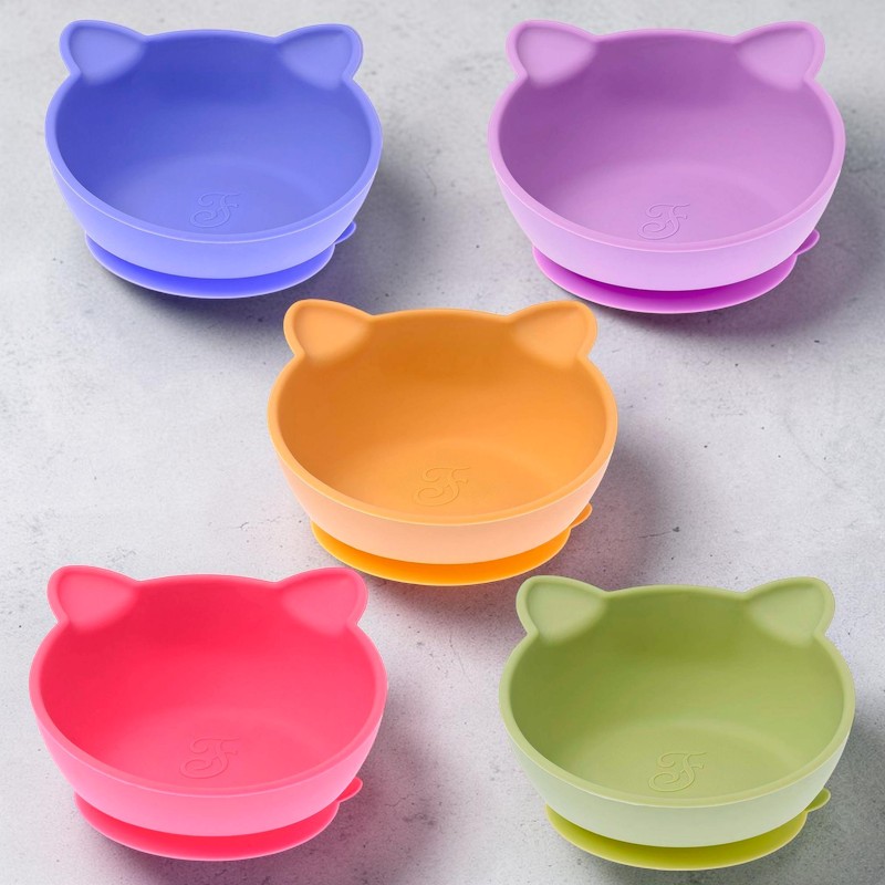 Fünf farbenfrohe Silikonschalen für Heimtiere, geformt wie Katzenköpfe mit kleinen Ohren, liegen auf hellgrauem Untergrund. Mit Saugnapfboden, in Lila, Violett, Orange, Pink und Hellgrün. Innen je ein 'F'-Logo.