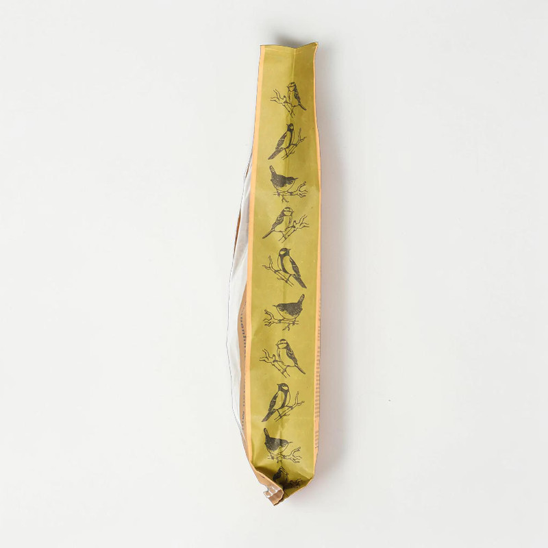 Un sachet haut et étroit jaune doré, debout, contient du millet en épis pour oiseaux. L'emballage montre des silhouettes d'oiseaux noirs sur des branches et indique une friandise naturelle pour oiseaux sauvages et d'ornement.