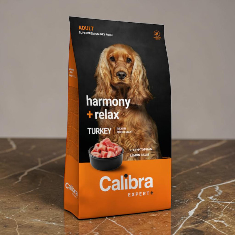 Aufrecht stehende orange-schwarze Calibra Expert+ Hundefuttertüte mit „harmony + relax“. Abgebildet sind ein brauner Cocker Spaniel und eine Schale mit gewürfeltem Truthahn. L-Tryptophan und Zitronenmelisse fördern Ruhe.