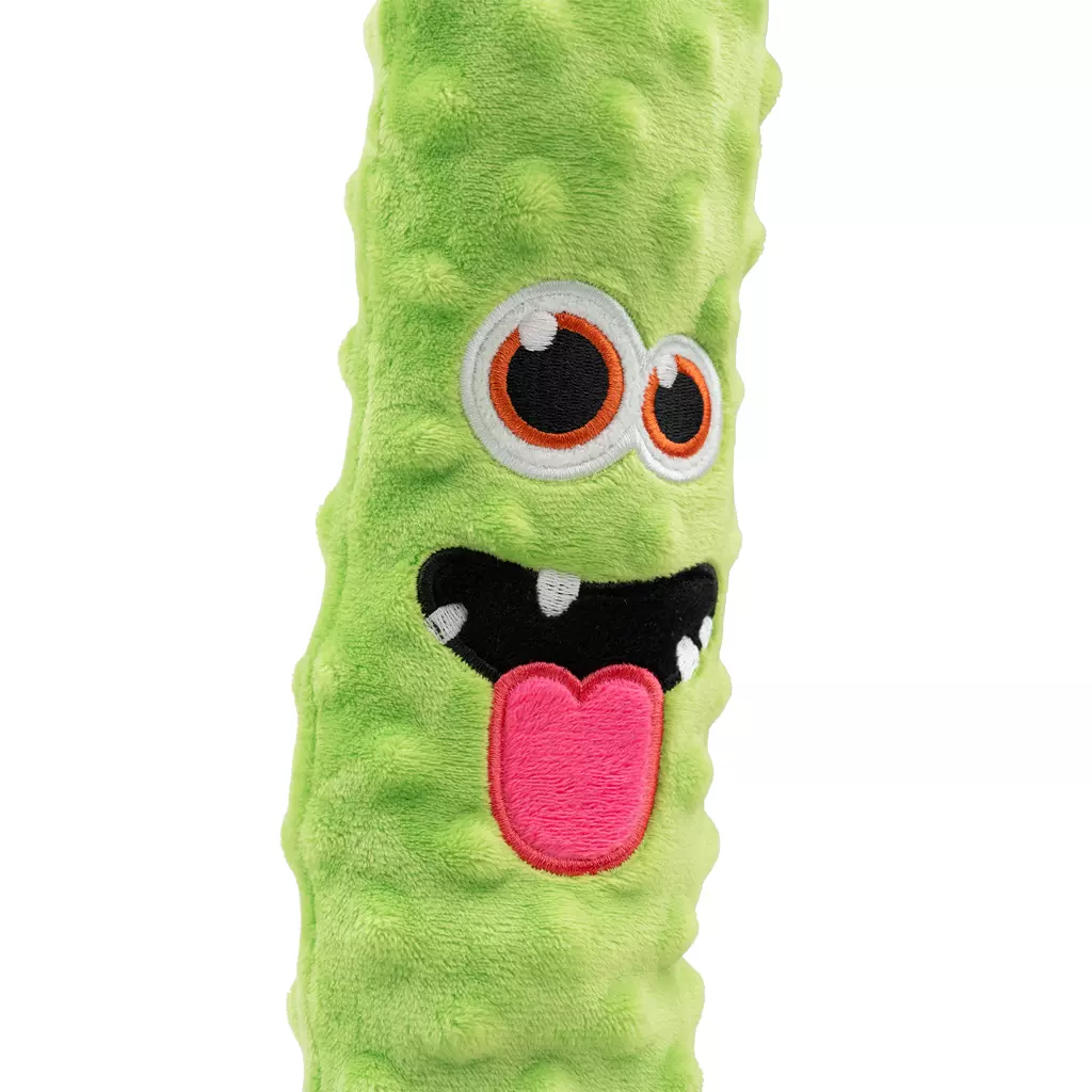 Un peluche o cuscino allungato, morbido e di colore verde chiaro, con una superficie ruvida che ricorda un cetriolo o un mostro. Presenta un viso buffo con grandi occhi arancioni e una bocca aperta con i denti.