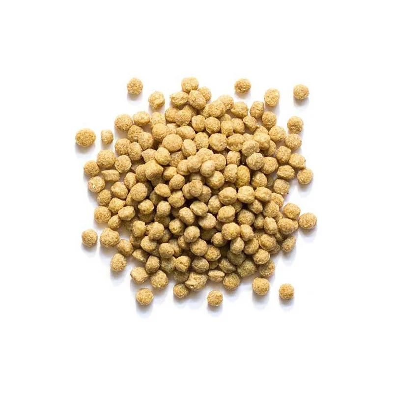 Mucchio di piccoli pellet di forma irregolare, di colore marrone chiaro, al centro di uno sfondo bianco. I pezzi granulari sembrano mangime secco o cereali con una superficie leggermente ruvida e strutturata. Singoli pellet sono sparsi qua e là.