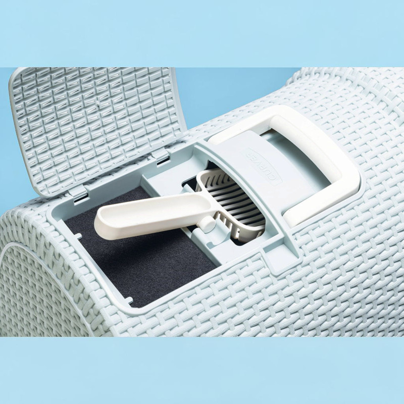 A closed ‘ Curver ’ cat litter tray in a rattan design, lightly tinted blue. The top lid is open, revealing an integrated compartment containing a white litter scoop and a paw-cleaning grid. A carrying handle is also visible.