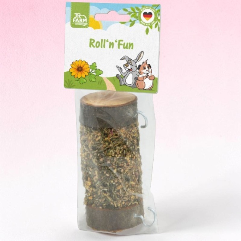 Pre-packaged cylindrical rodent toy: a wooden log filled with dried herbs and seeds, with metal hooks at each end. The packaging features the JR Farm logo, ‘Roll’n’Fun’, a flower and a cartoon rabbit/guinea pig.