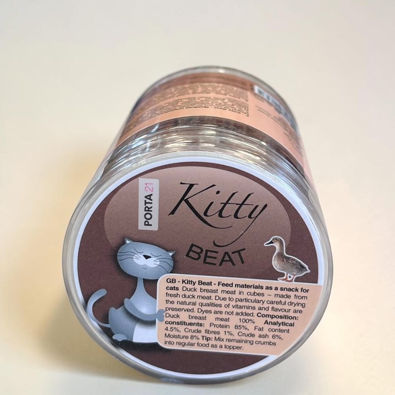 Barquette cylindrique transparente avec cubes de viande de canard lyophilisés pour chats. Étiquette marron : « Kitty Beat Canard Pur » avec un chat et un canard. 100 % magret de canard, séché sans additifs, idéal en cas d'allergies.