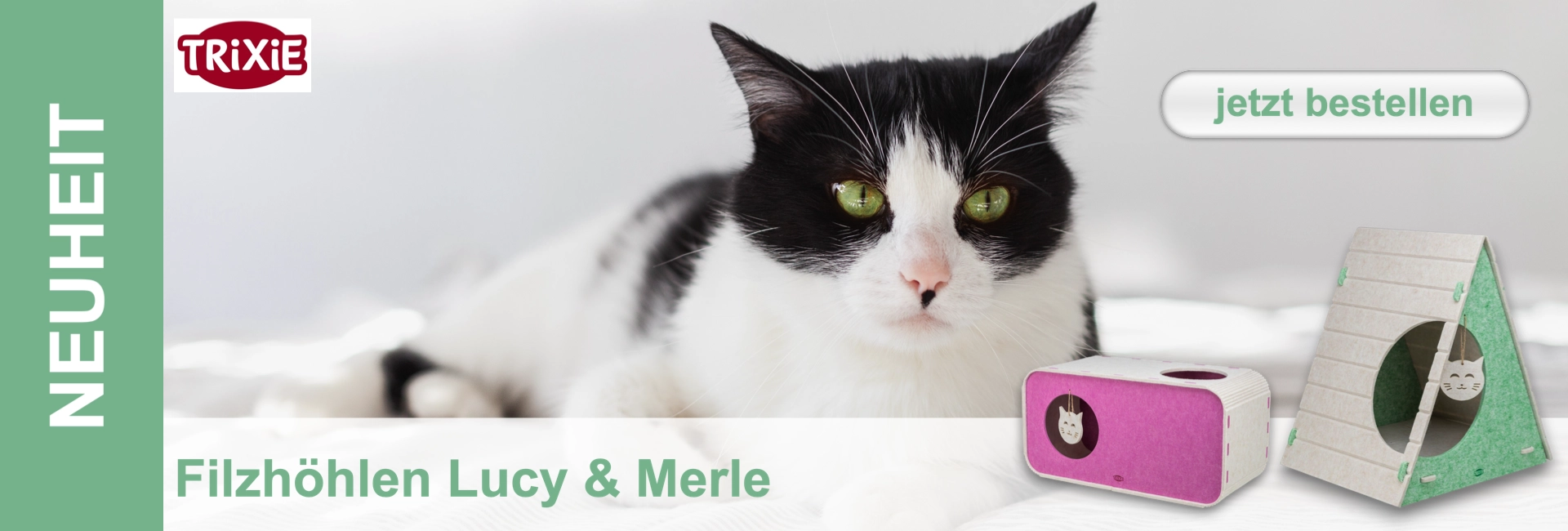 Schwarz-weiße Katze mit leuchtend grünen Augen blickt in die Kamera, entspannt vor hellem Hintergrund. Davor zwei moderne Filzhöhlen: quaderförmig weiß mit pink innen und runder Öffnung sowie dreieckig beige/grün, mit Katzenkopf-Anhänger.