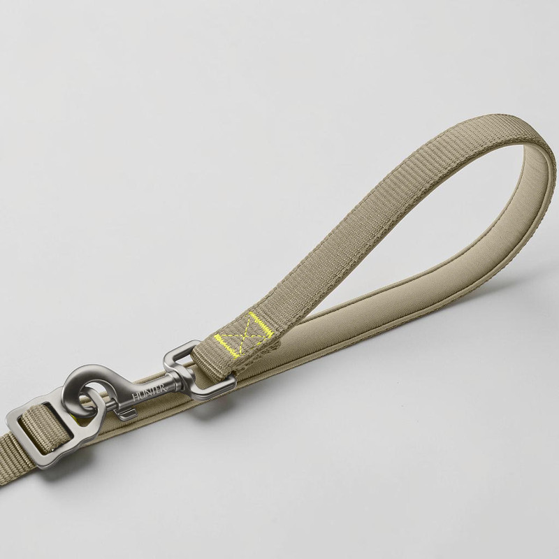 Detailansicht einer robusten graugrünen Action-Hundeleine mit ergonomischer, neoprengepolsterter Handschlaufe. Leichter Aluminium-Sicherheitskarabiner mit "HUNTER"-Gravur und Schnellverschluss. Gelbe Nähte; Komfort und Sicherheit.