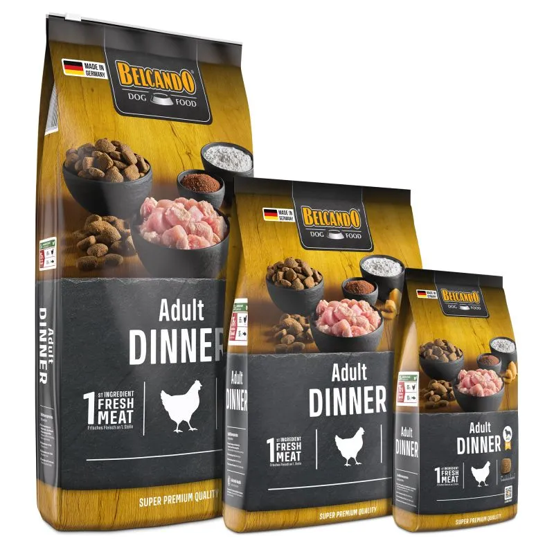 Tre confezioni sovrapposte di mangime secco Belcando Adult Dinner, con superficie effetto legno e parte inferiore scura. Nell’immagine: ciotole con crocchette, carne fresca di pollame e polveri. Scritta: «Adult Dinner», «1st ingredient Fresh Meat».