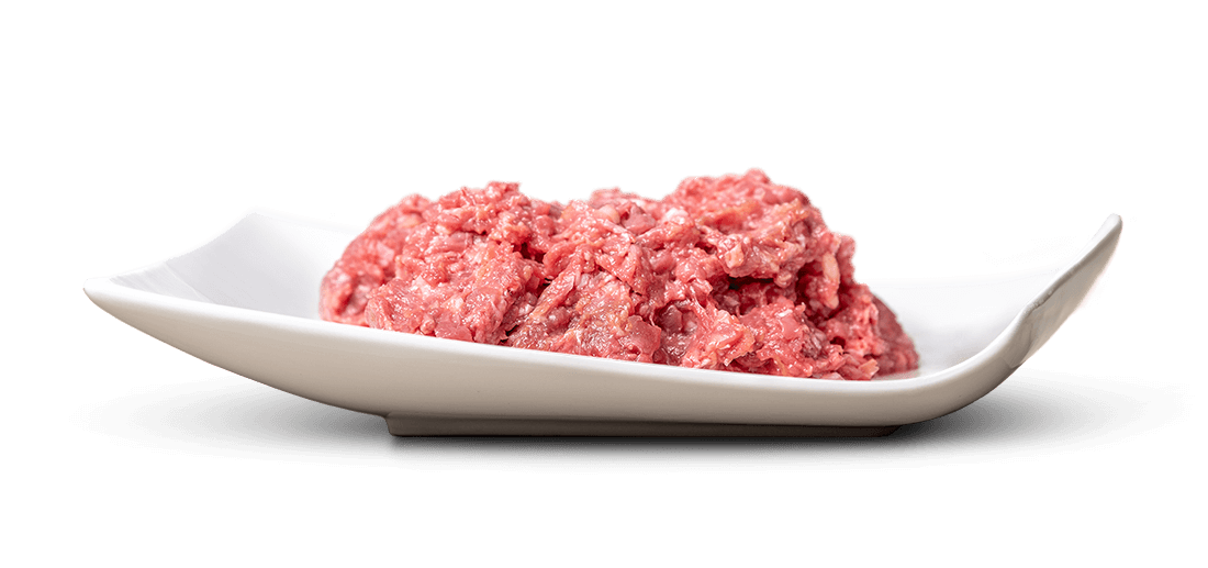 De la viande hachée crue, fraîche, humide et brillante, aux teintes rose-rouge, est disposée en un tas lâche sur un plat de service blanc, plat et rectangulaire. Sa texture granuleuse est bien visible. Au centre, sur un fond d'un blanc immaculé.