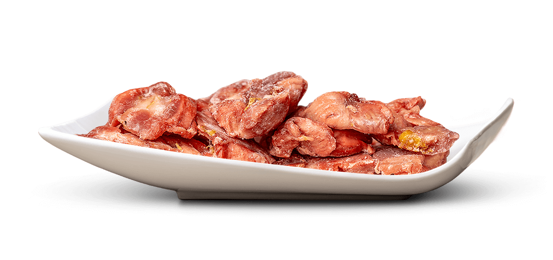 Getrocknete, rötlich-rosa Erdbeerstücke liegen in einer eleganten, weiß glänzenden Schale. Die Stücke sind leicht gezuckert oder gefrostet, teils mit gelblichen Einschlüssen, und wirken wie eine süße Leckerei.