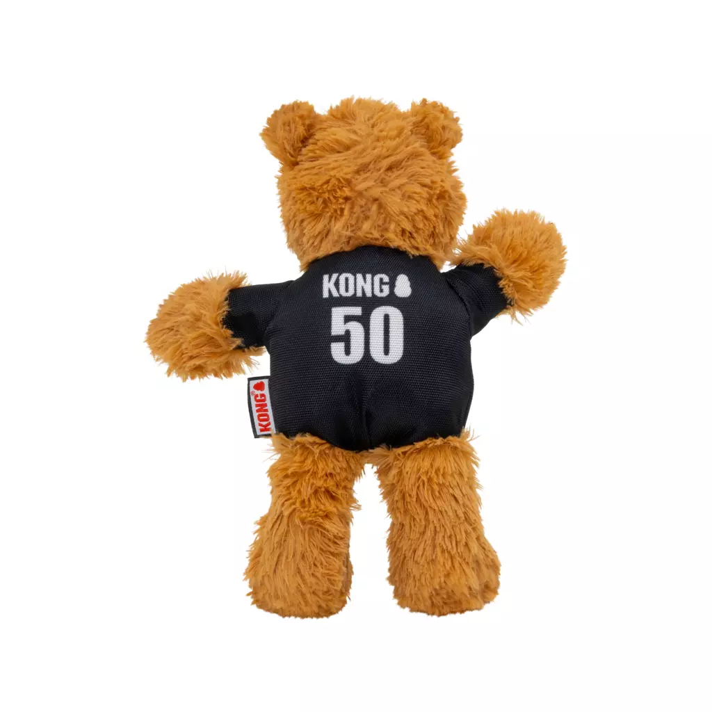 Orsacchiotto di peluche marrone visto di spalle su sfondo bianco. Indossa una maglietta nera con la scritta bianca "Kong" e il numero "50" in grande sulla schiena. Sul fianco è visibile un'etichetta rossa Kong. Le braccia sono leggermente sollevate.