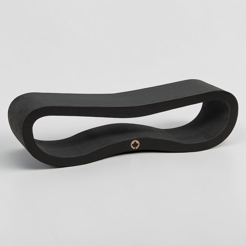 An elongated black object with a wavy, curved shape resembling a horizontal figure of eight or a loop. The surface is slightly textured. In the lower curve is a small, round, copper-coloured logo featuring a maple leaf.